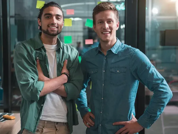 Two smiling entrepreneurs in a workspace, standing side by side and helping customers with City Service Link